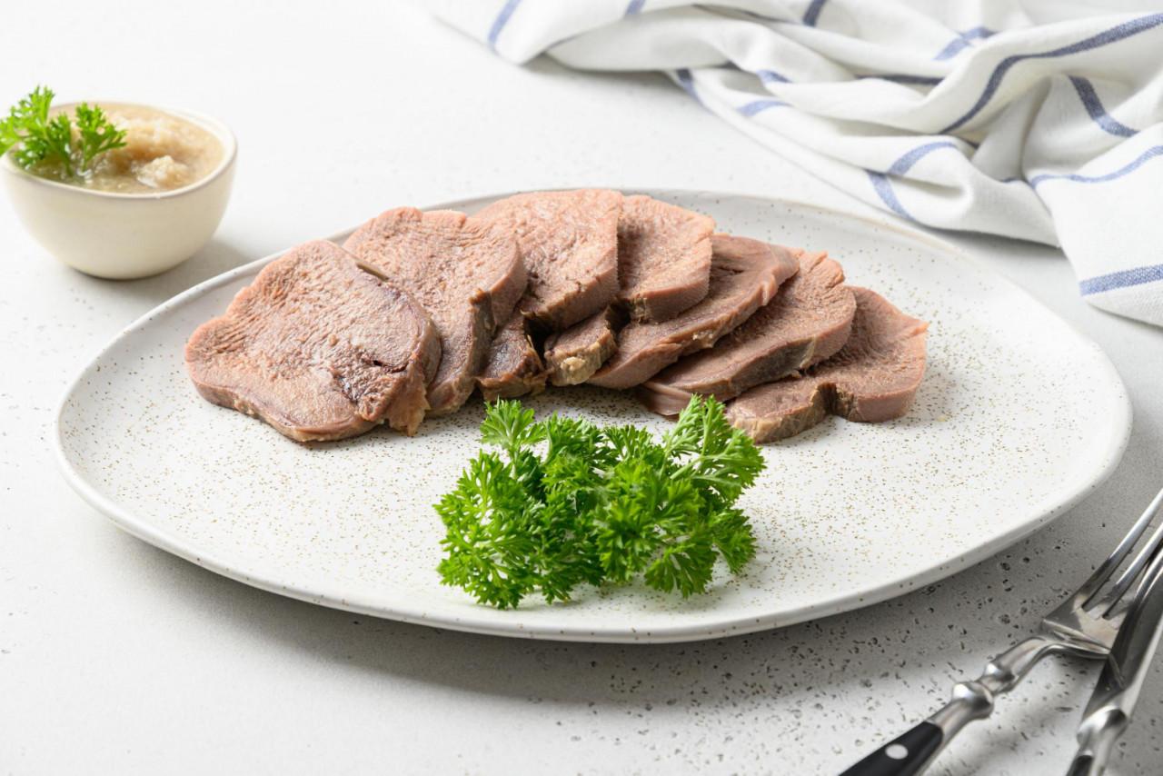 sliced beef tongue with horseradish sauce white table close up